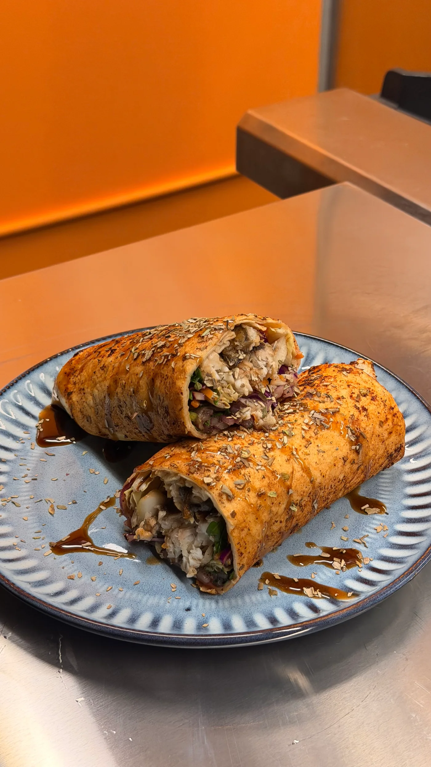 Grilled barramundi wrap cut in half, filled with fresh salad and served on a blue plate