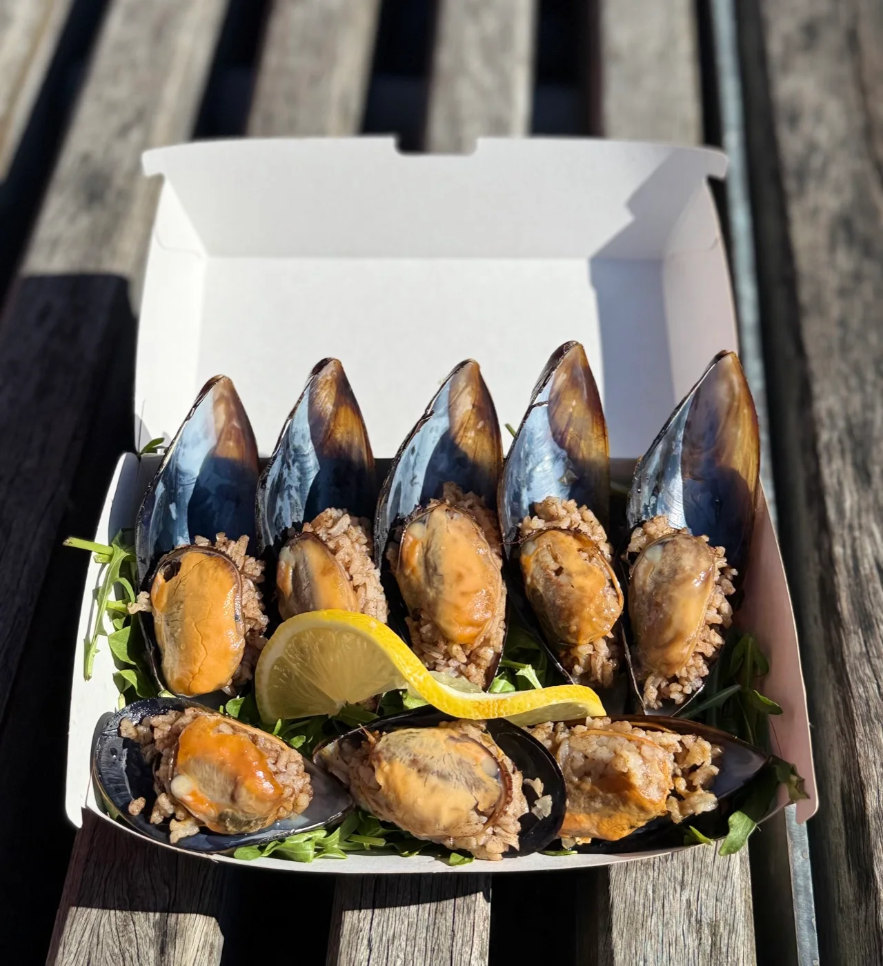 Open mussels filled with spiced rice, served with fresh lemon